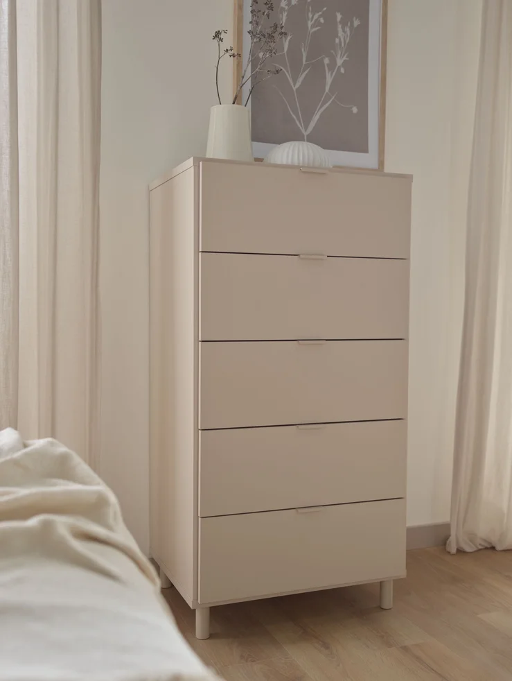Wysoka komoda z szufladami na tle jasnej ściany